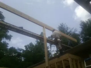 Carpenter setting a ridge beam over a new addition frame — Ice Dam Removal by Roofing Brothers in Lakeside