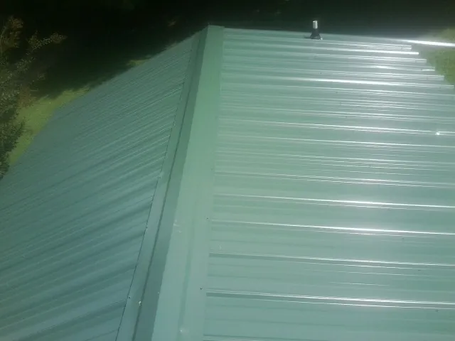 New green metal panels meeting at the ridge of a roof — Flat Roof Repair work by our crew in Lakeside