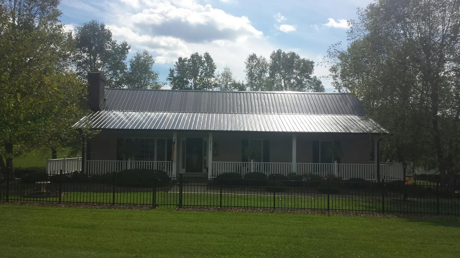 Gray metal roof on a brick ranch with a full width front porch — Gutter Guard Installation work by our crew in Lakeside